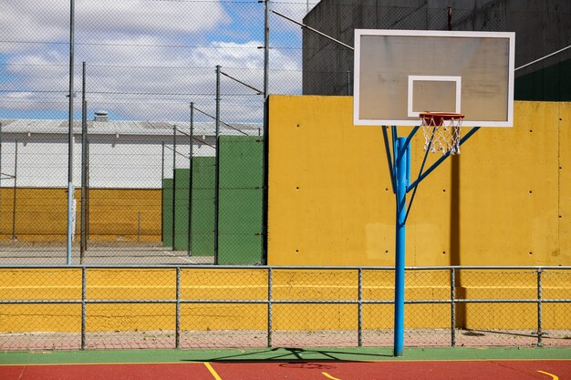 Cesta de basquete cercada por cercas em um playground sob a luz do sol durante o dia