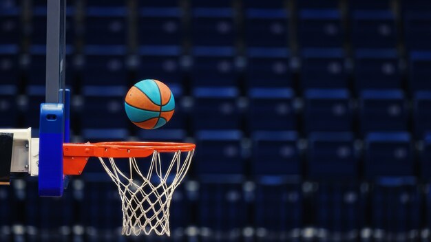 Cesta de basquete com uma bola sobre os assentos vazios da arena esportiva