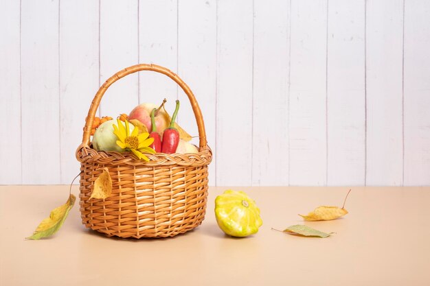 Cesta de colheita de outono com abobrinha de maçã de milho e pimentão em um fundo de madeira decorado com flor de outono