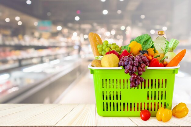 Cesta de compras cheia de frutas e legumes na mesa de madeira com supermercado desfocado fundo desfocado com luz bokeh