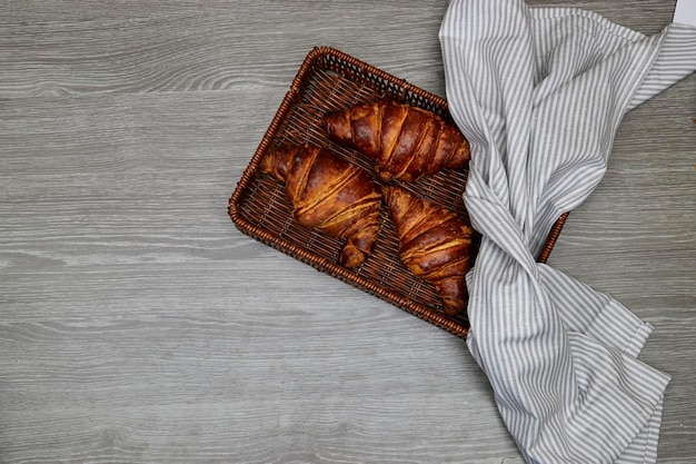 cesta de esparto halfah com croissants frescos na mesa de madeira