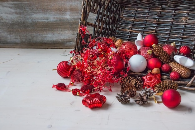 Cesta de Natal com presentes de decoração com bastões de doces de fita de cetim vermelha pinhas guirlandas vermelhas e brancas sobre fundo branco de madeira Feliz conceito de férias de ano novo