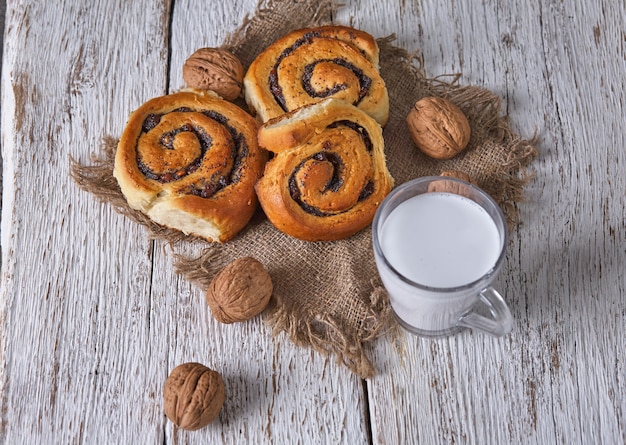 Cesta de pães caseiros com geléia, servida na mesa de madeira velha com nozes e copo de leite