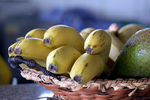 Cesta de palha com cacho de bananas maduras