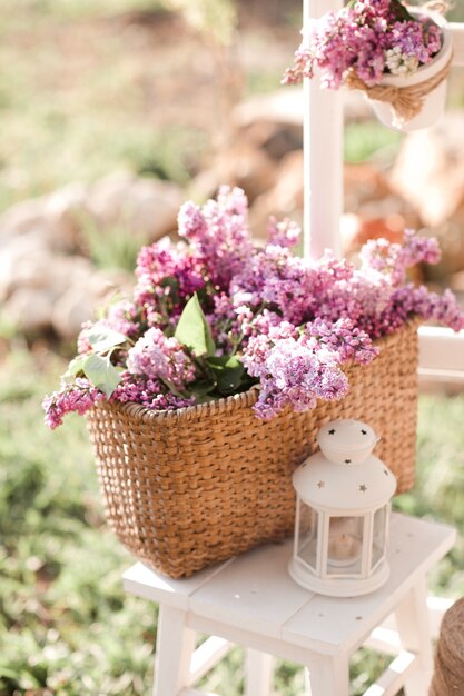 Cesta de palha com flores lilás na mesa de madeira branca