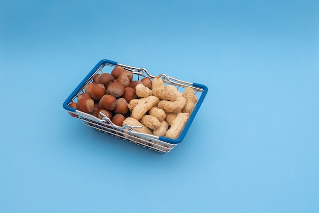 Cesta de supermercado com amendoim e avelã em uma mesa azul