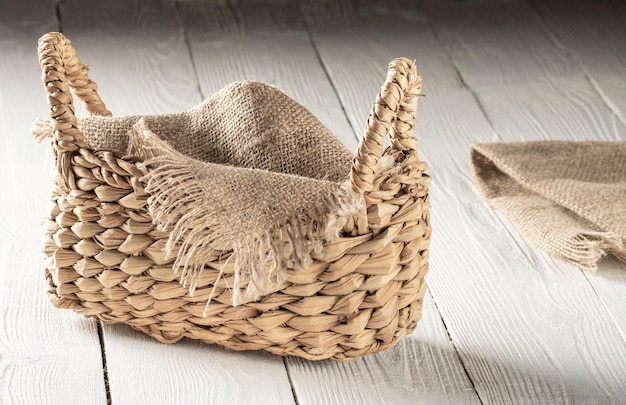 Cesta de talos de junco com guardanapos de serapilheira em uma mesa camponesa de madeira