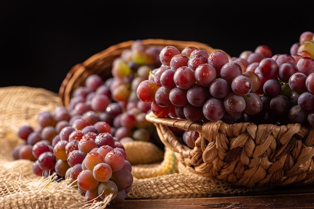 Cesta de uvas com lindas uvas e tecido rústico em foco seletivo de madeira rústica