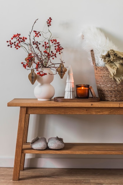 Cesta de velas de decoração de Natal com cobertores em um banco de madeira de carvalho em uma aconchegante sala de estar