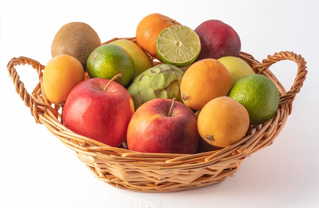 Cesta de vime cheia de frutas frescas e variadas em um fundo branco