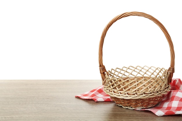 Cesta de vime vazia e pano na mesa de madeira contra o espaço de fundo branco para o feriado de Páscoa de texto