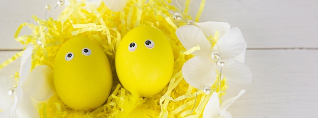 Cesta decorativa con huevos amarillos decorados con plumas al sol