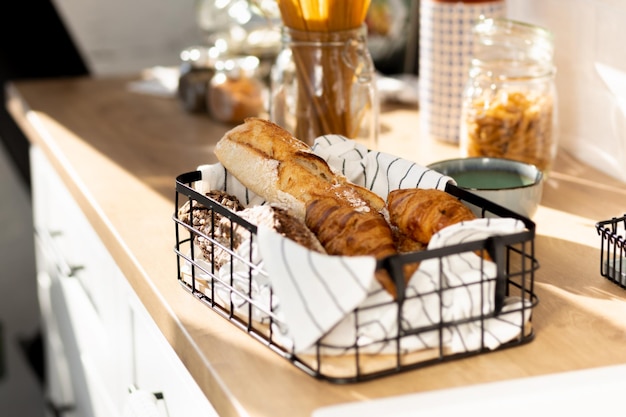 Cesta con diversos productos horneados caseros, baguette, ciabatta y croissant en la mesa de la cocina de madera, espacio de copia