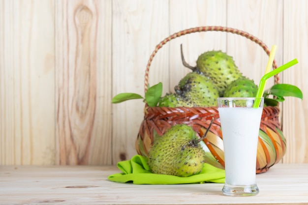 Cesta e suco do soursop ou creme espinhoso apple ou annona muricata l na tabela de madeira.