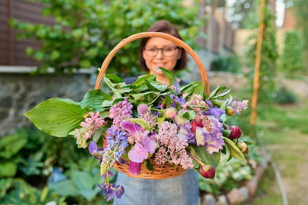 Cesta con flores de jardín de primavera en manos de mujer