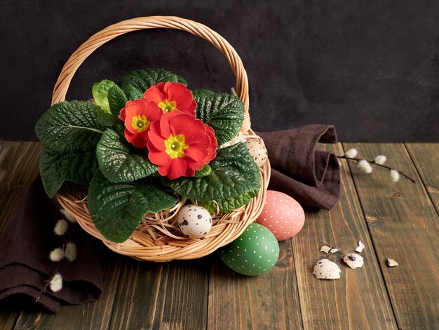 Cesta con flores de maceta de onagra roja y sauce de coño sobre una mesa de