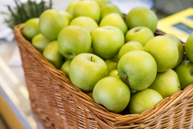 Cesta con frutas frescas maduras de manzana verde a la venta en la tienda de comestibles, en cesta de mimbre