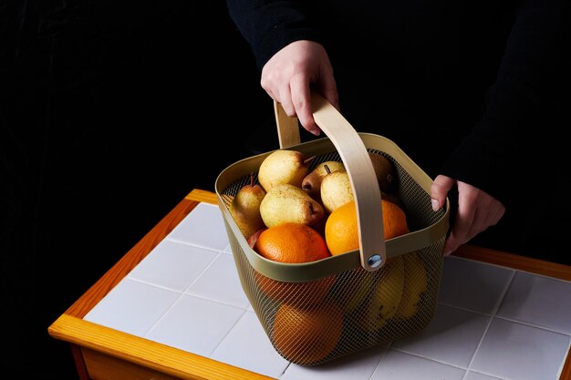 Cesta de frutas en la mesa sostenida en las manos