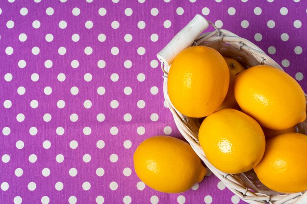 Cesta de limones sobre mantel morado punteado