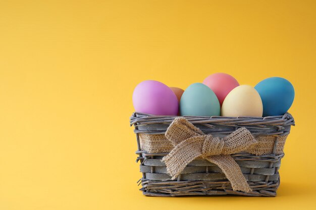 Cesta de madera con hermosos huevos coloridos Feliz Pascua, buen espacio en blanco para una tarjeta de felicitación.