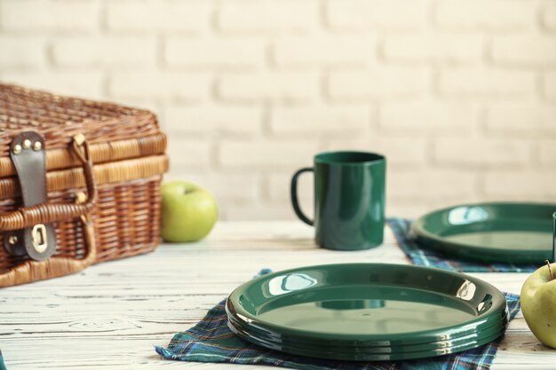 Cesta de madera para picnic con platos, tazas y cubiertos de cerca