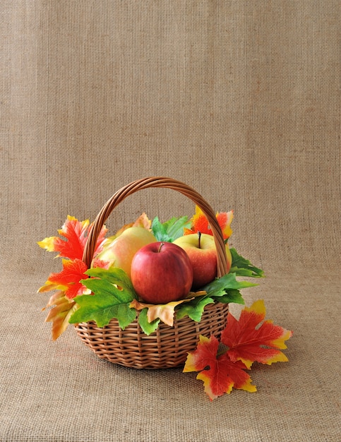 Cesta de manzanas con hojas de otoño