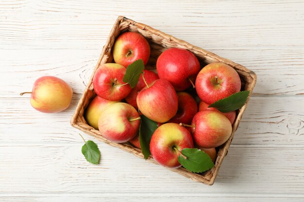 Cesta con manzanas en la mesa de madera blanca