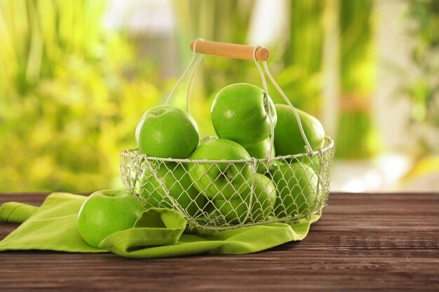 Cesta con manzanas verdes frescas sobre mesa de madera