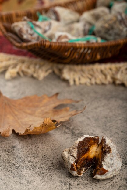 Cesta de mimbre de caquis dulces secos sobre mesa de piedra.