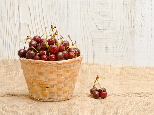 Cesta de mimbre con cerezas en una mesa de madera