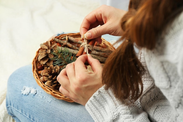 Cesta de mimbre con decoración navideña en manos de mujer, primer plano