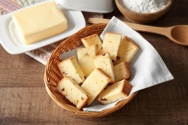 Cesta de mimbre con delicioso pastel de mantequilla en rodajas sobre mesa de madera