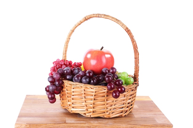 Cesta de mimbre con frutas en una pequeña escalera de madera aislada en blanco