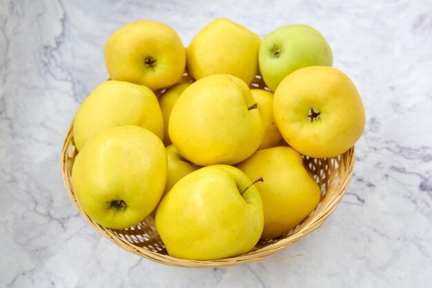 cesta de mimbre con manzanas verdes doradas