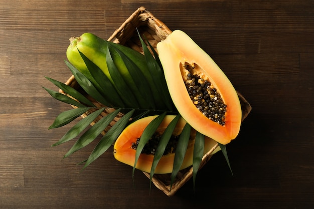 Cesta de mimbre con papaya en mesa de madera