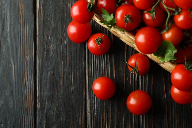 Cesta de mimbre con tomate cherry sobre fondo de madera