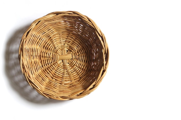 Cesta de mimbre vacía en fondo blanco vista superior