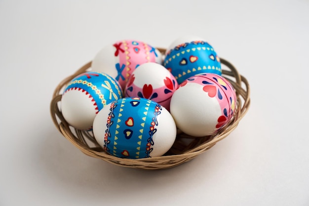 Foto cesta de pascua con huevos de pascua en fondo blanco.