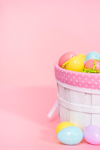 Cesta de Pascua con huevos de Pascua sobre un fondo rosa.