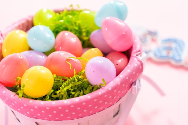 Cesta de Pascua con huevos de Pascua sobre un fondo rosa.