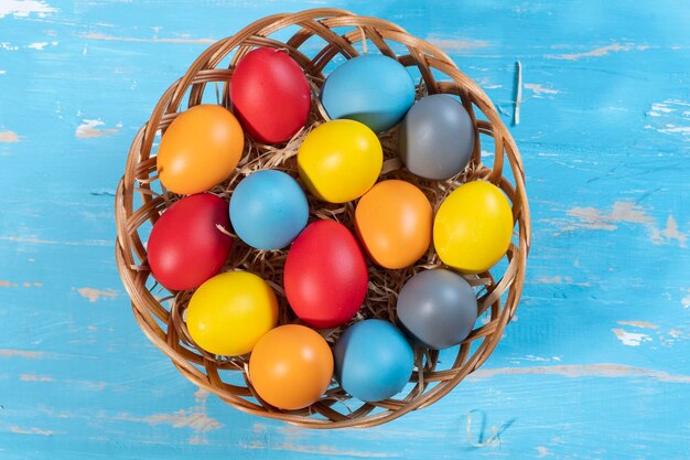 Foto cesta de pascua con paja y huevos de colores