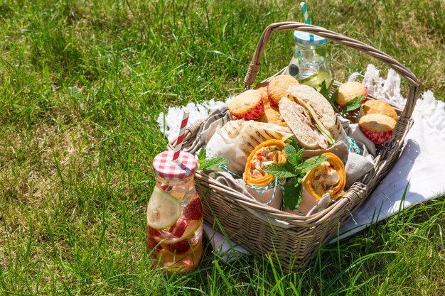 Cesta de picnic con comida en césped verde y soleado