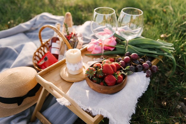 Foto cesta de picnic con fresas y uvas sobre la verde hierba