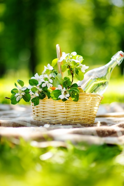 Cesta de picnic con frutas, flores y agua en la botella de vidrio.