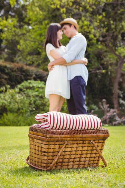 Cesta de picnic en el jardín y pareja abrazados