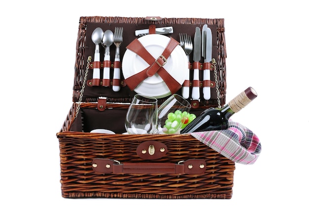 Cesta de picnic de mimbre con vajilla de comida y mantel aislado en blanco