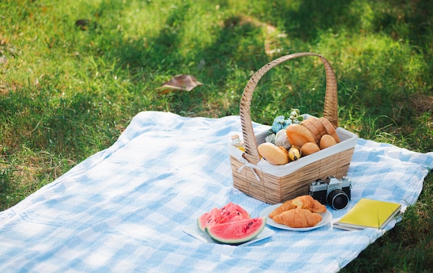 Cesta de picnic con pan, comida y fruta.