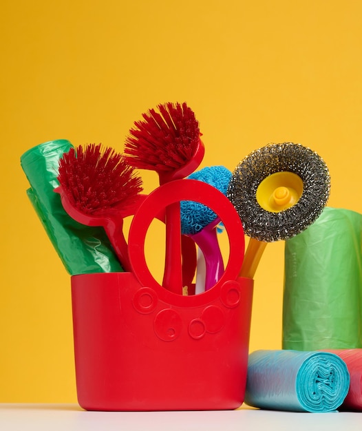 Cesta de plástico con cepillos desinfectantes en una botella sobre un fondo amarillo