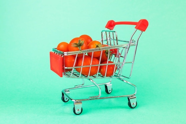 Foto cesta de supermercado, en el interior hay tomates cherry maduros.