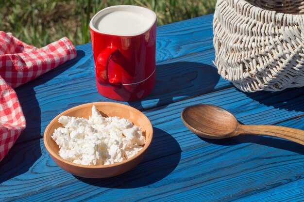 Cesta, una taza de leche y requesón sobre una mesa de tableros azules